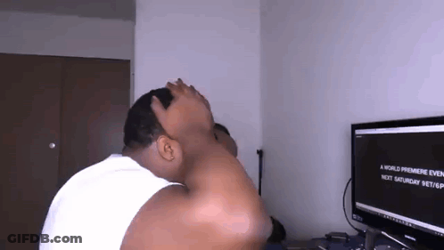 A Man Is Sitting In Front Of A Computer Screen Covering His Face With His Hand . GIF