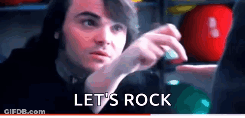 A Man Is Sitting In Front Of A Computer With The Words Let 'S Rock Written On The Bottom . GIF