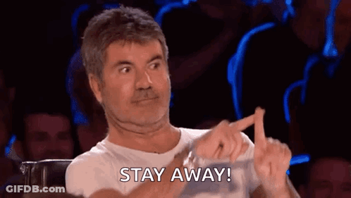 A Man Is Sitting In Front Of A Crowd Making A Funny Face And Pointing At Something . GIF