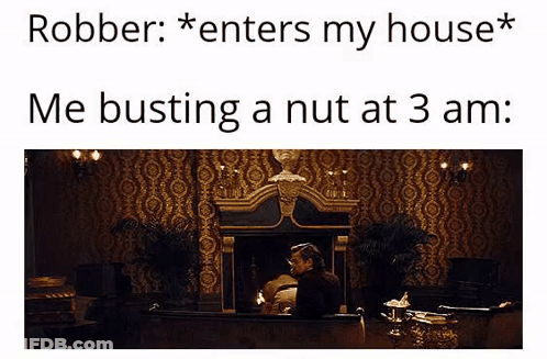 A Man Is Sitting In Front Of A Fireplace In A Room With A Statue On The Wall . GIF