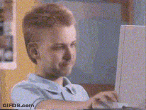 A Man Is Sitting In Front Of A Laptop Computer And Smiling . GIF