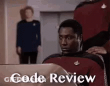 A Man Is Sitting In Front Of A Laptop With The Words `` Code Review '' Written On The Screen . GIF
