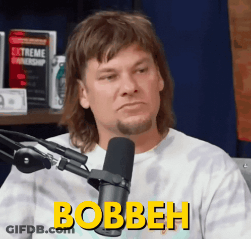 A Man Is Sitting In Front Of A Microphone And The Word Bobbeh Is On His Shirt GIF