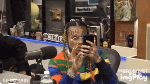 A Man Is Sitting In Front Of A Microphone Looking At His Phone GIF
