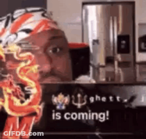 A Man Is Sitting In Front Of A Sign That Says `` Is Coming ! '' GIF