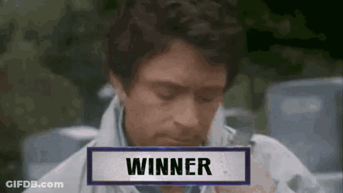 A Man Is Sitting In Front Of A Sign That Says " Winner " GIF