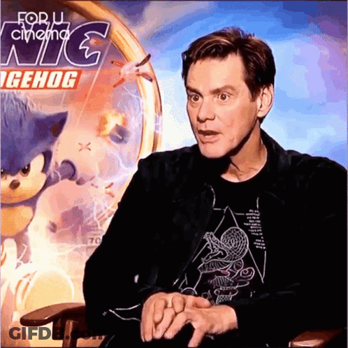A Man Is Sitting In Front Of A Sonic The Hedgehog Poster GIF
