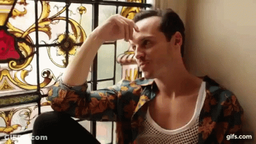A Man Is Sitting In Front Of A Stained Glass Window And Looking Out . GIF