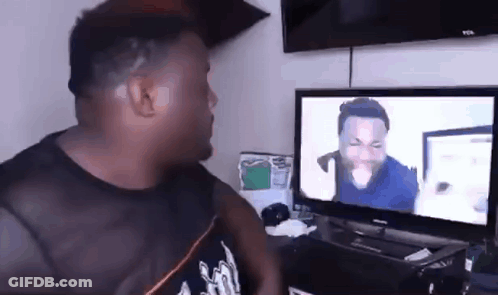 A Man Is Sitting In Front Of A Television Watching A Video . GIF