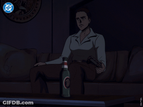 A Man Is Sitting In Front Of A Television With A Dc Logo On The Screen GIF
