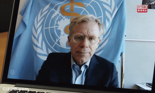 A Man Is Sitting In Front Of A United Nations Flag On A Laptop GIF