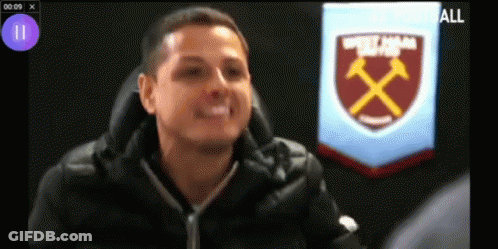A Man Is Sitting In Front Of A West Ham Badge GIF