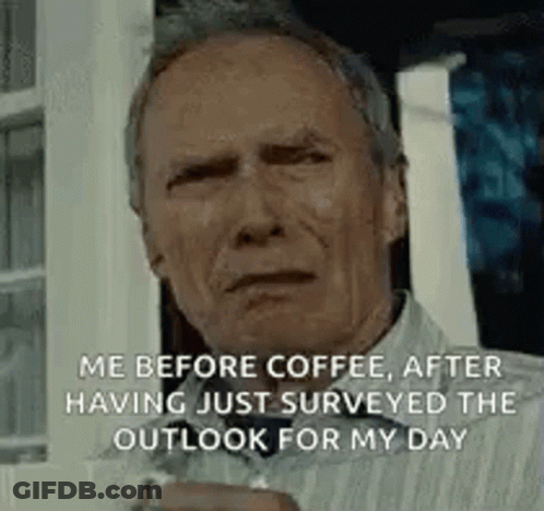 A Man Is Sitting In Front Of A Window Holding A Cup Of Coffee And Looking At The Camera . GIF