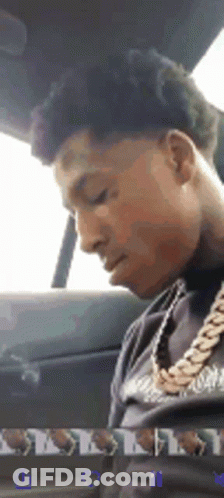 A Man Is Sitting In The Back Seat Of A Car Wearing A Gold Chain Around His Neck . GIF