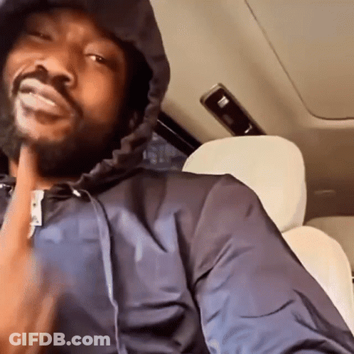 A Man Is Sitting In The Back Seat Of A Car Wearing A Hooded Jacket . GIF