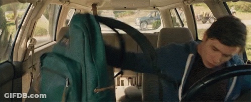 A Man Is Sitting In The Back Seat Of A Car With A Backpack On His Back . GIF