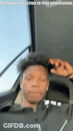 A Man Is Sitting In The Back Seat Of A Car With His Eyes Closed And His Hand On His Head . GIF