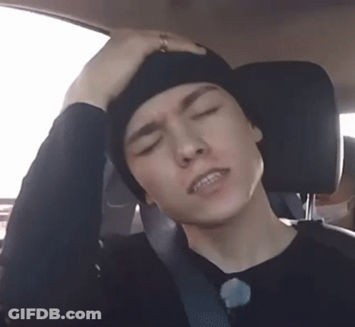 A Man Is Sitting In The Back Seat Of A Car With His Hand On His Head . GIF