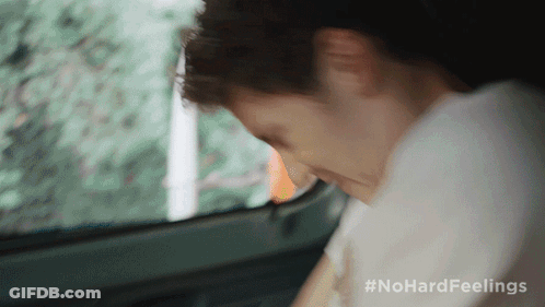 A Man Is Sitting In The Back Seat Of A Car With His Head Down GIF