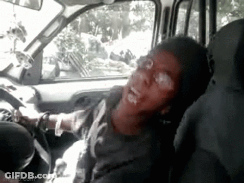 A Man Is Sitting In The Driver 'S Seat Of A Car And Making A Funny Face . GIF