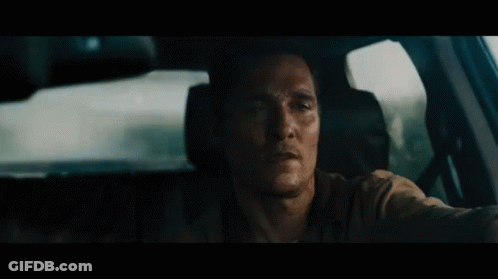 A Man Is Sitting In The Driver 'S Seat Of A Car Looking Out The Window . GIF