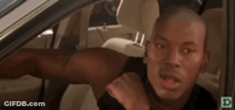 A Man Is Sitting In The Driver 'S Seat Of A Car Making A Face . GIF