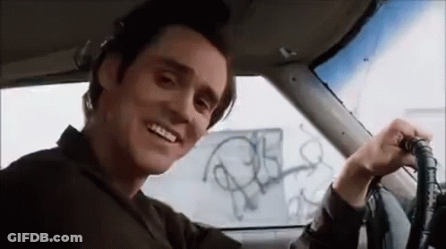 A Man Is Sitting In The Driver 'S Seat Of A Car Smiling . GIF