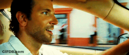 A Man Is Sitting In The Driver 'S Seat Of A Car While A Woman Holds His Hand Over His Head . GIF