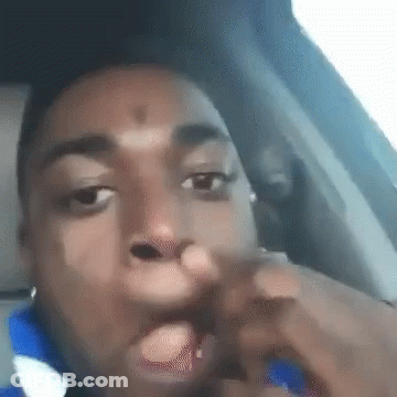 A Man Is Sitting In The Driver 'S Seat Of A Car With His Hand In His Mouth . GIF