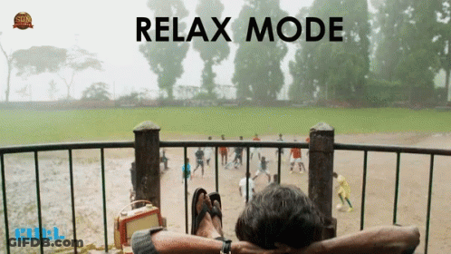 A Man Is Sitting On A Balcony With His Feet Up And The Words Relax Mode Behind Him GIF