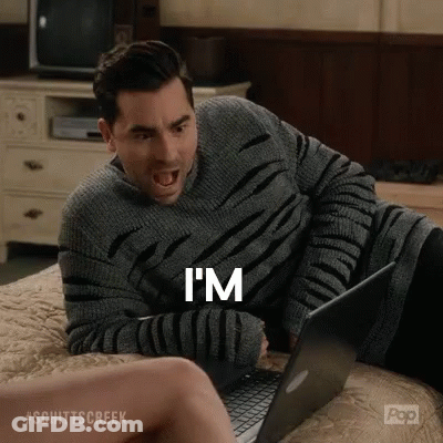 A Man Is Sitting On A Bed Using A Laptop Computer And Yelling . GIF