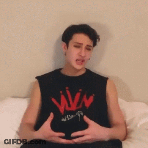 A Man Is Sitting On A Bed With His Hands On His Belly . GIF