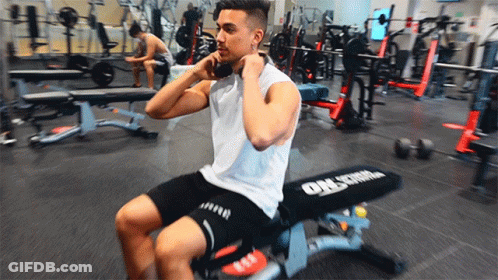 A Man Is Sitting On A Bench In A Gym That Says Orlstrom GIF