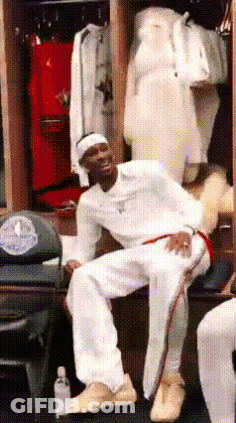 A Man Is Sitting On A Bench In A Locker Room Wearing White Pants GIF