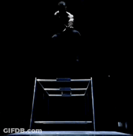 A Man Is Sitting On A Chair In The Dark With His Legs Crossed GIF
