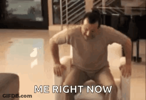 A Man Is Sitting On A Chair With His Legs Crossed And The Words `` Me Right Now '' Written On The Screen . GIF