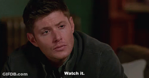 A Man Is Sitting On A Couch And Saying `` Watch It '' While Looking At The Camera . GIF
