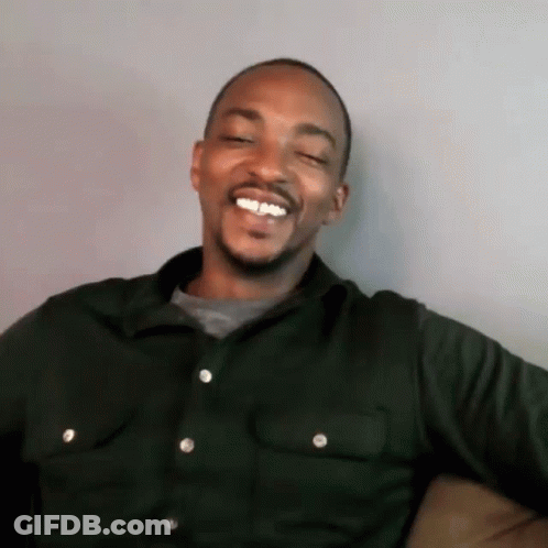 A Man Is Sitting On A Couch And Smiling With His Eyes Closed . GIF