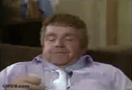 A Man Is Sitting On A Couch Drinking A Glass Of Water . GIF