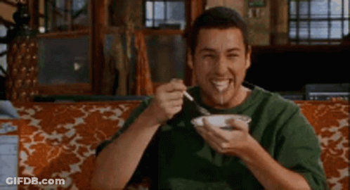 A Man Is Sitting On A Couch Eating A Bowl Of Food With A Fork . GIF