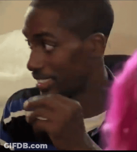 A Man Is Sitting On A Couch Eating A Sandwich While Looking At Something . GIF