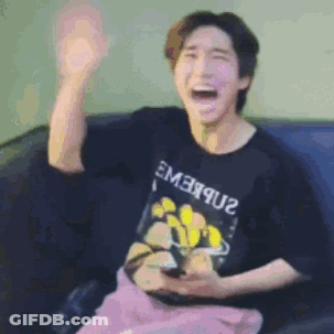 A Man Is Sitting On A Couch Holding A Cell Phone And Making A Funny Face . GIF