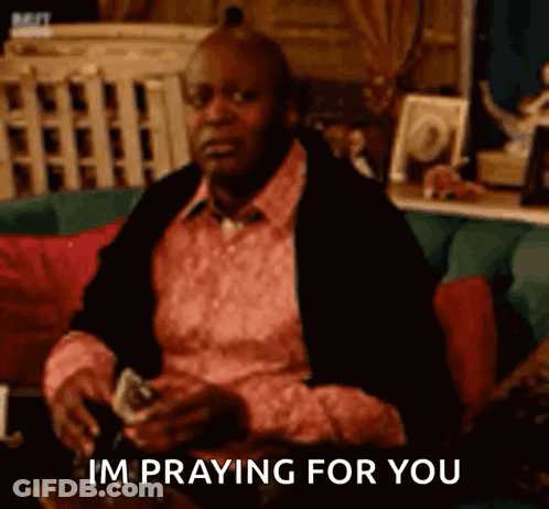 A Man Is Sitting On A Couch Holding A Glass Of Wine And Playing Cards And Saying `` Im Praying For You '' GIF