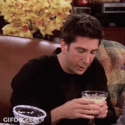 A Man Is Sitting On A Couch Holding A Margarita In His Hand . GIF