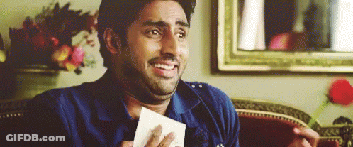 A Man Is Sitting On A Couch Holding A Piece Of Paper And Making A Funny Face . GIF