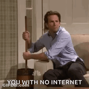 A Man Is Sitting On A Couch Holding A Toilet Brush And A Mop . GIF