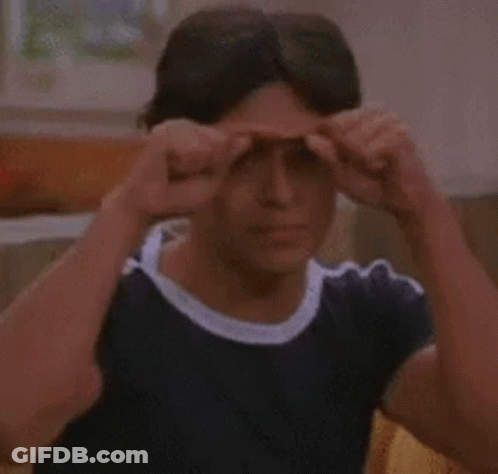 A Man Is Sitting On A Couch Holding His Hands To His Eyes . GIF