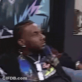 A Man Is Sitting On A Couch In Front Of A Wall With A Picture On It . GIF