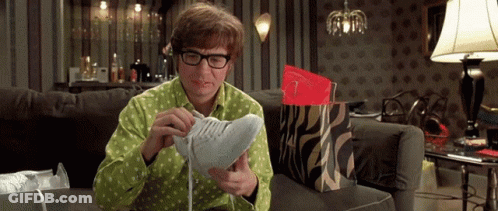 A Man Is Sitting On A Couch Looking At A Pair Of Shoes GIF