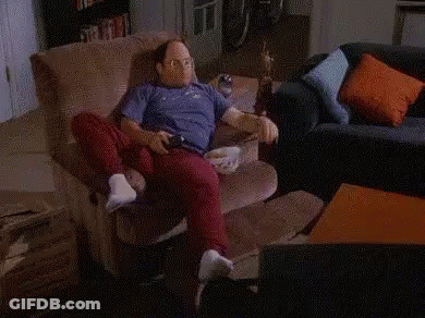 A Man Is Sitting On A Couch Next To A Shelf Full Of Sodas And Snacks GIF